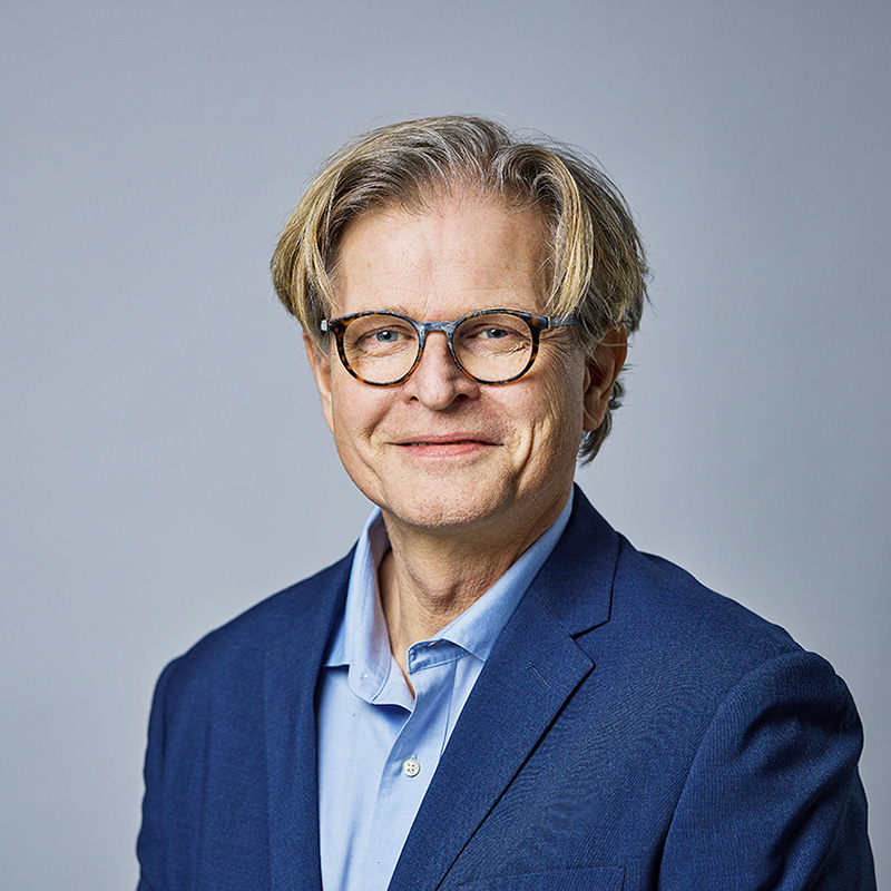 Portrettbilde av mann med briller og blå jakke