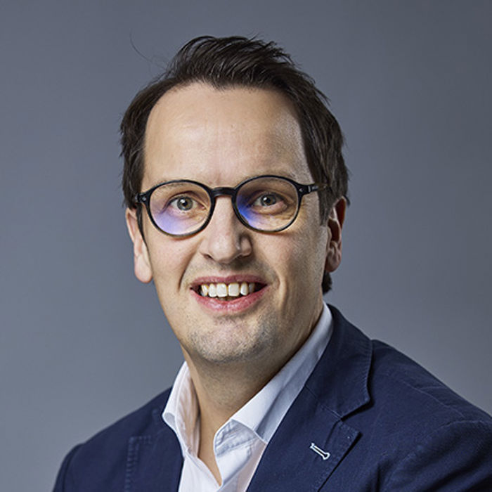 Blid mann med hvit skjorte og blå dressjakke